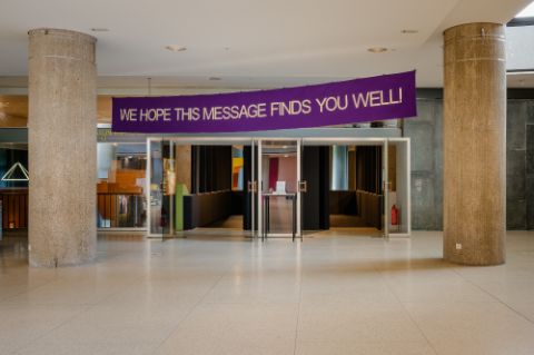 Mona Vătămanu and Florin Tudor in collaboration with Dinu Bodiciu, We hope this message finds you well! (2025), textile banner. Photo: Hanna Wiedemann/HKW